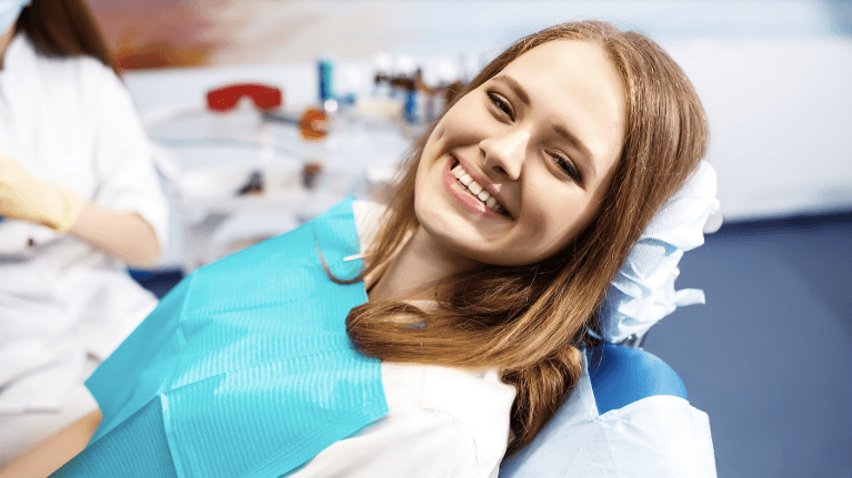 red haired woman smiling in a dental chair