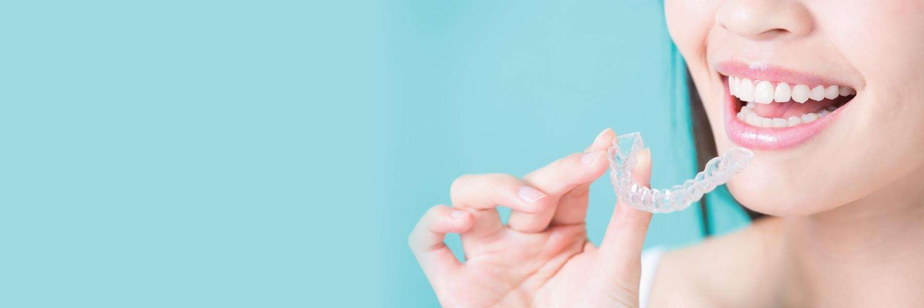 Close up of woman using Invisalign aligner on her teeth