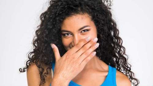 woman missing teeth covering her mouth